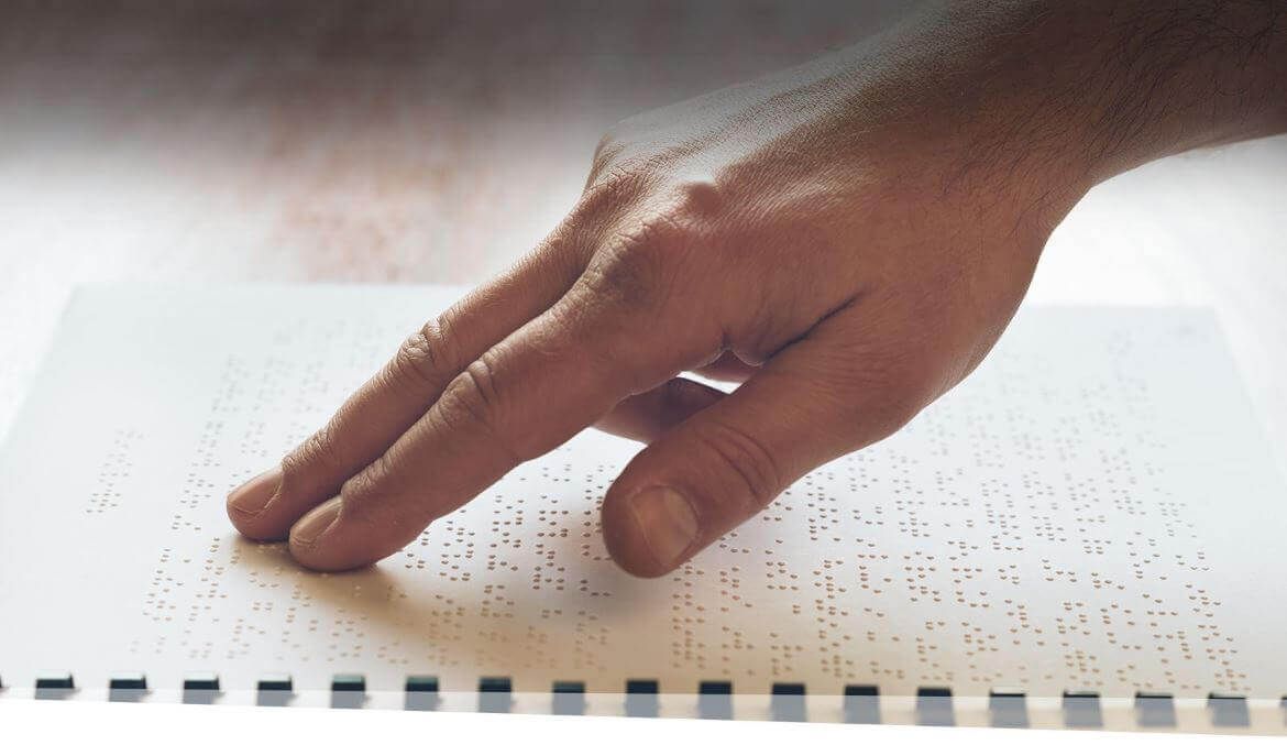 Visually impaired elderly person learning to read by touch using Braille.